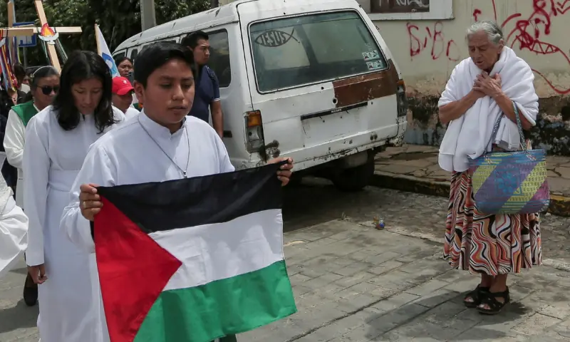 A woman prays as an acolyte holding a Palestinian flag walks with faithful participating in a pilgrimage organised by a Catholic Church to pray for peace amid the ongoing conflict in Gaza, in San Cristobal de Las Casas, Chiapas, Mexico, on September 28, 2025. &mdash; Reuters