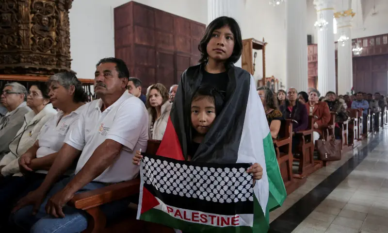 A girl, wearing a Palestinian flag, stands with another girl, who is holding a combination flag with details of a Palestinian keffiyeh and a Palestinian flag with &ldquo;Palestine&rdquo; written in the center, at a cathedral after participating in a pilgrimage organised by the Catholic Church to pray for peace amid the ongoing conflict in Gaza, in San Cristobal de las Casas, Chiapas, Mexico, on September 28, 2025. &mdash; Reuters