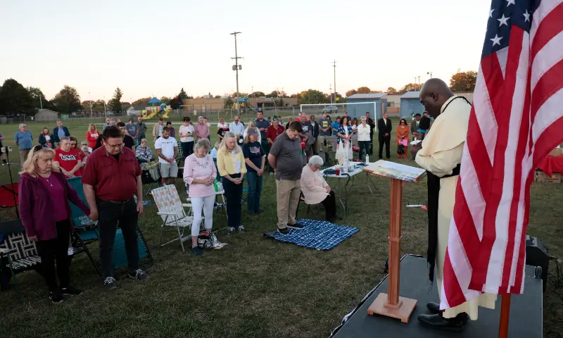 Pastor Fr. Georges Bidzogo (R) leads a prayer vigil outside Holy Redeemer Church in Burton, Michigan, on September 28, 2025, a few miles from Grand Blanc, where a gunman opened fire at a Mormon church earlier today. &mdash; AFP