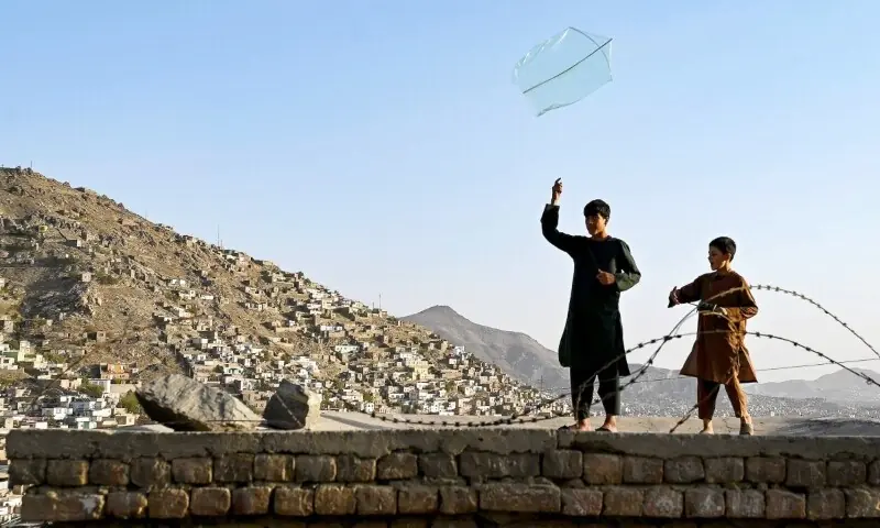 Afghan boys fly a kite on the rooftop of a house in Kabul on September 29, 2025, following a nationwide telecom outage. &mdash;  AFP