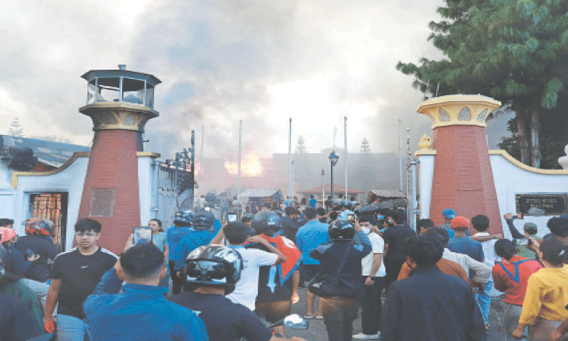 People gather as smoke billows from the burning President House, set ablaze by protesters in Kathmandu on Tuesday, a day after demonstrations over social media prohibitions and corruption by the government. Nepal&rsquo;s president called for national unity after two days of violent protests that forced the premier to quit.&mdash;AFP