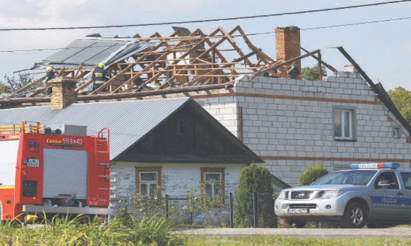 FIREFIGHTERS work on the destroyed roof of a house in Wyryki, Poland, after the drone strike.&mdash;Reuters