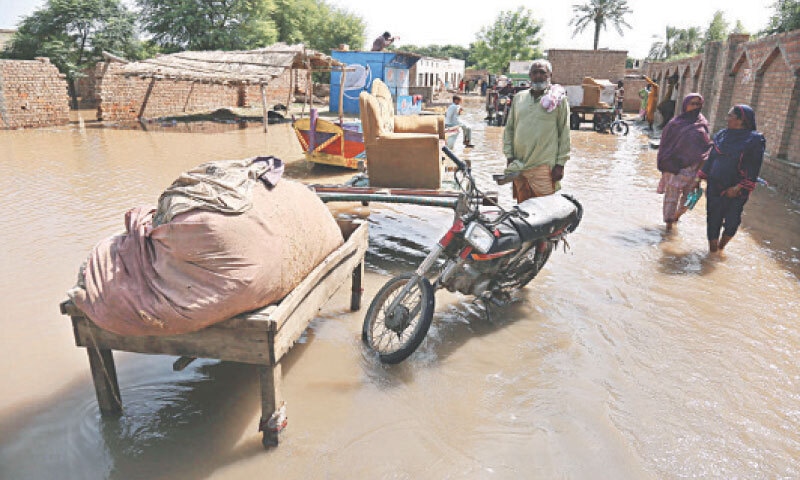 MUZAFFARGARH: Flood-affected villagers gather their belongings as they wait to be rescued.—APP