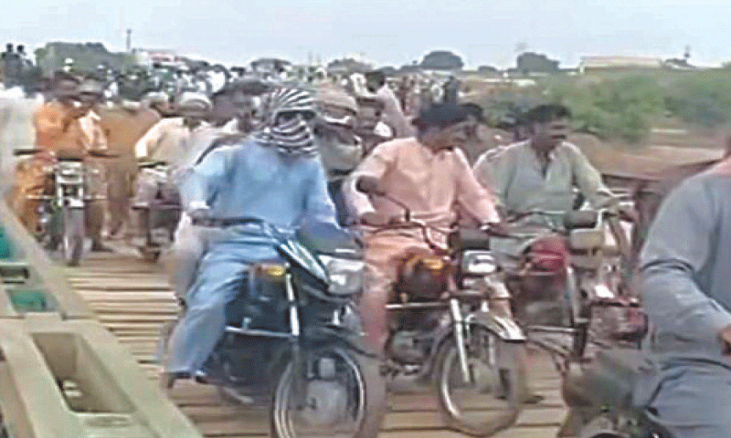 TOBA TEK SINGH: Motorcyclists use a Bailey bridge made functional at Adda Kalaira. &mdash; Dawn