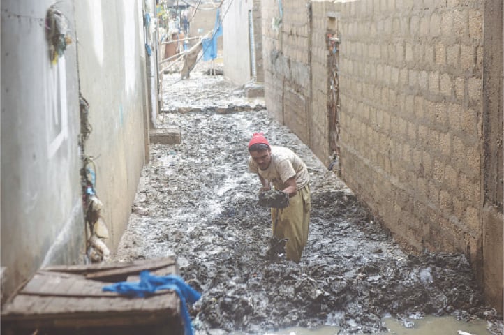  A resident of Shafiq Colony cleans the street outside his home after returning on Thursday, following the family&rsquo;s evacuation on Tuesday due to flooding&nbsp;in&nbsp;the&nbsp;area.&mdash;Fahim Siddiqi/White Star 