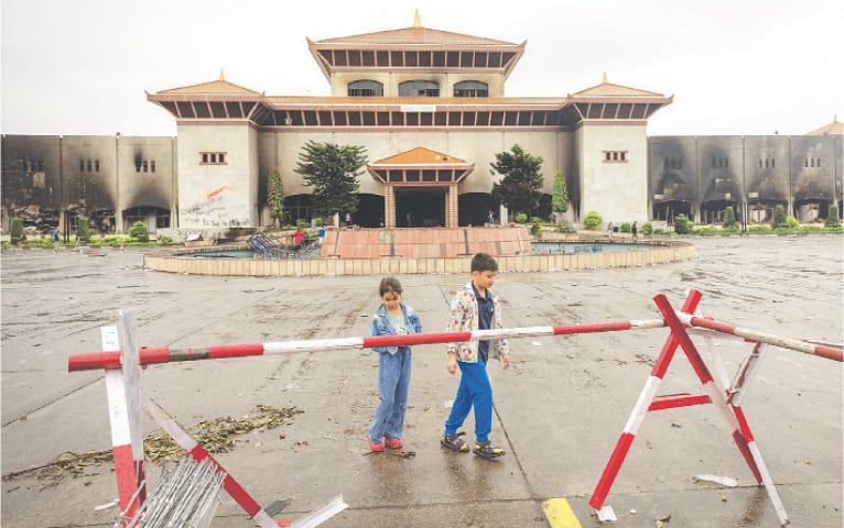  Children stroll in front of the parliament building in Kathmandu, which still bears the scars after being set on fire by protesters.&mdash;Reuters 