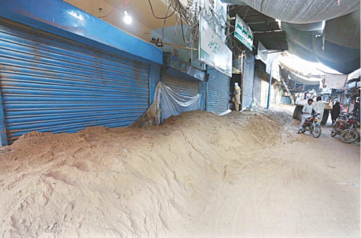 JALALPUR PIRWALA: Desperate to save their goods, traders have sealed shutters of their shops with polythene sheets and mud. &mdash; APP