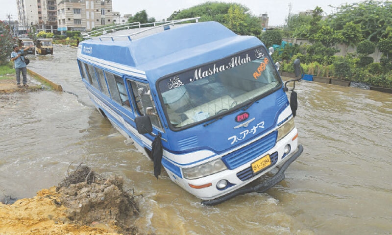 A coaster gets stuck in a hidden pothole on a road submerged by floodwater in the Gulzar-i-Hijri area. &mdash;Online