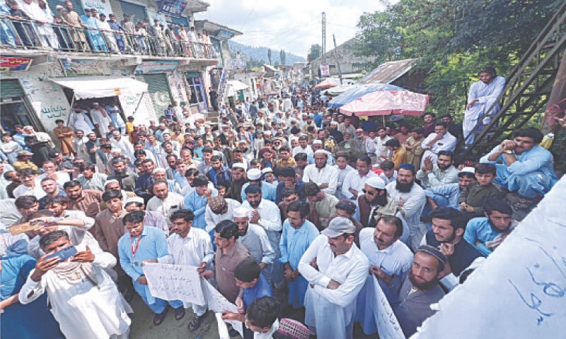 Residents of Pir Khana area in Kana tehsil hold placards and shout slogans during a protest. &mdash;  Dawn