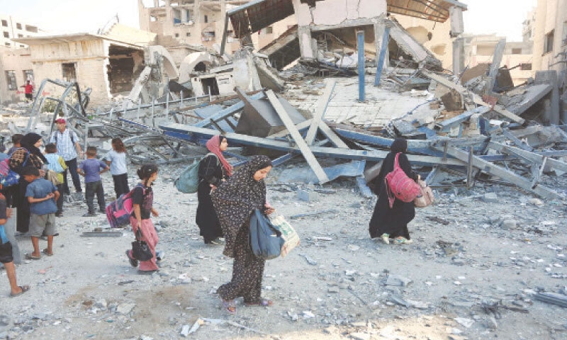 Displaced Palestinians carry their belongings as they walk past the rubble of a building, levelled in an overnight Israeli strike in Gaza City.&mdash;AFP