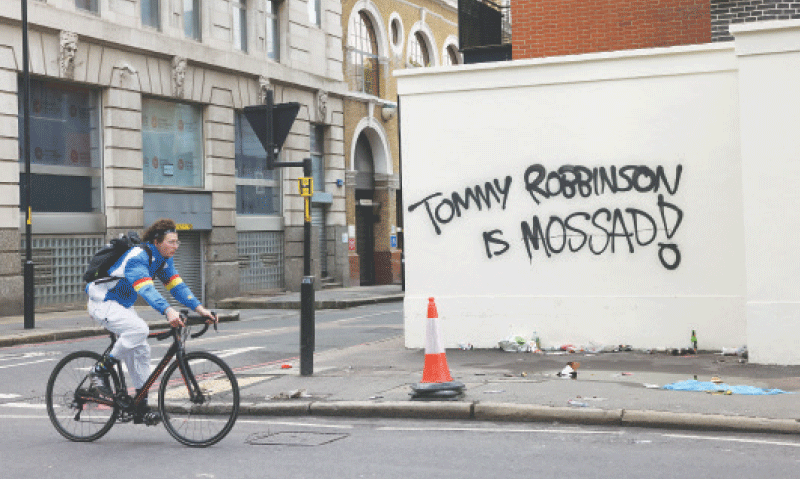 London: A cyclist rides past a wall painted with grafitti the day after an anti-immigration rally organised by anti-immigration activist Tommy Robinson.&mdash;Reuters
