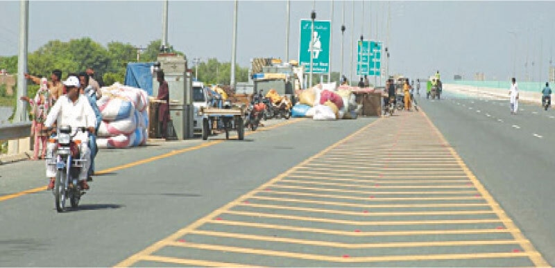People displaced by flooding gather on the Sukkur-Multan Motorway M-5 near Jalalpur Pirwala, waiting for support and shelter.—White Star People displaced by flooding gather on the Sukkur-Multan Motorway M-5 near Jalalpur Pirwala, waiting for support and shelter.—White Star