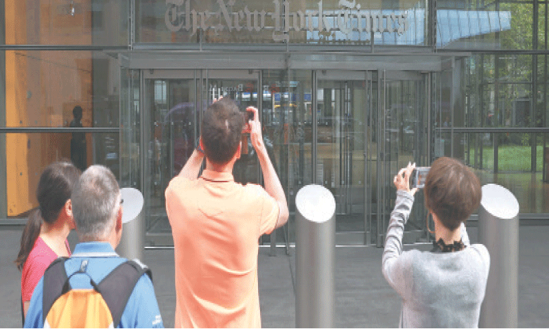 PASSERS-BY take photos of the New York Times building after President Donald Trump filed the defamation lawsuit.&mdash;AFP