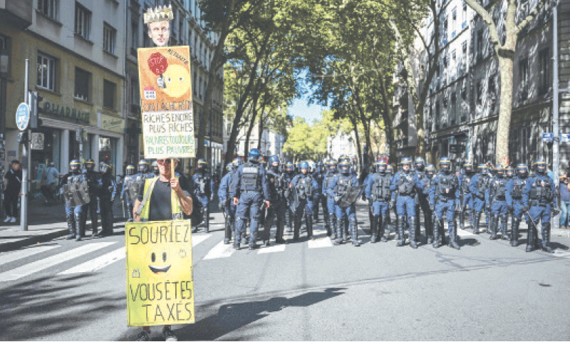 A LONE protester holds a banner as riot police gather behind him in Lyon, eastern France. &mdash; AFP
