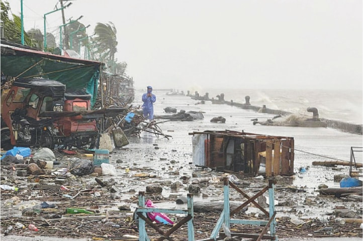 A MAN stands near debris on a waterfront road amid heavy rain brought by Typhoon Ragasa in Aparri, the Philippines.&mdash;AFP
