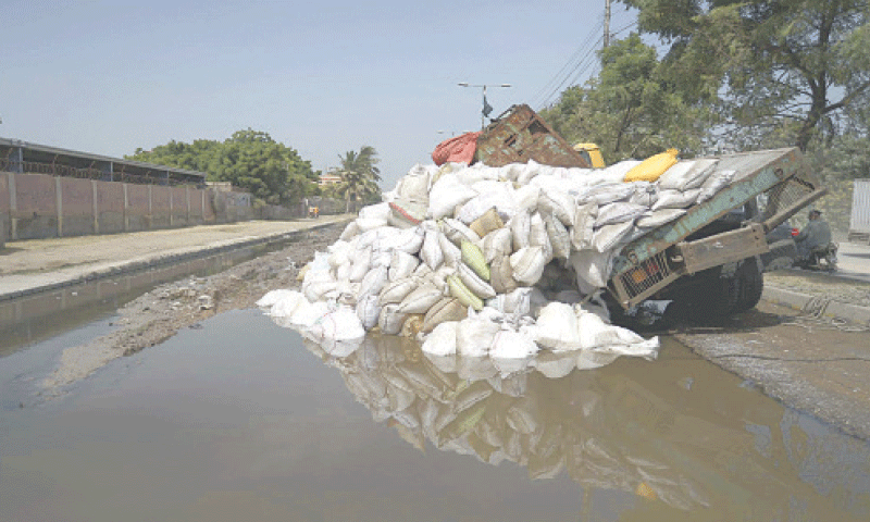 A portion of the truck&rsquo;s load tumbled off after it hit a pothole submerged by sewage in Malir Halt.&mdash;PPI