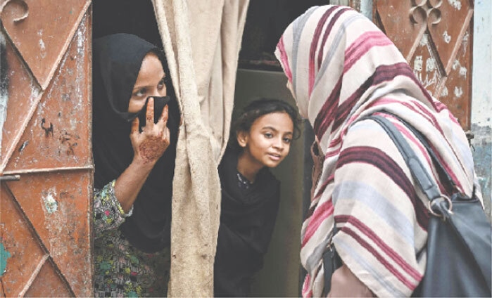 A health worker speaks with a woman during a door-to-door HPV vaccination drive in Karachi.—AFP