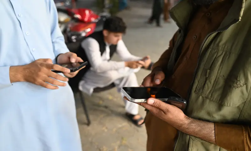 Afghan men use their mobile phones in Kabul on October 1, 2025. Mobile networks and the internet were restored across Afghanistan on October 1, 48 hours after the Taliban authorities shut down telecommunications. &mdash; AFP