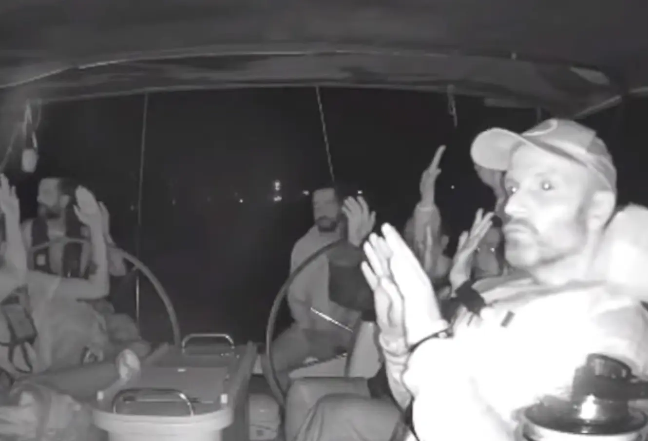 A screenshot from a livestream shows flotilla members aboard the Meteque vessel raising their hands as Israeli forces intercept the Global Sumud Flotilla