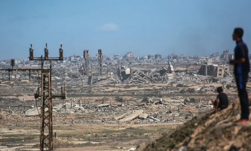Palestinians watch smoke billowing during Israeli strikes, upon arrival on a coastal path northwest of Nuseirat refugee camp as they are displaced southward from Wadi Gaza following an Israeli announcement of closing Al-Rashid road on October 1, 2025. &mdash; AFP