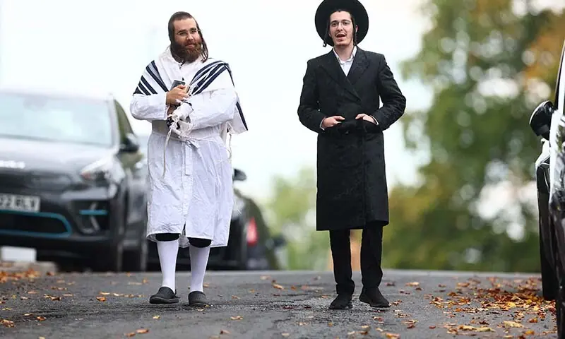 Members of the local Jewish community walk along the street near the Synagogue of Heaton Park Congregation in Crumpall, North Manchester, the United Kingdom on October 2. - AFP