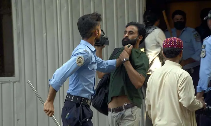 A policeman grabs a journalist by the shirt during a raid on the National Press Club in Islamabad on October 2. — Dawn