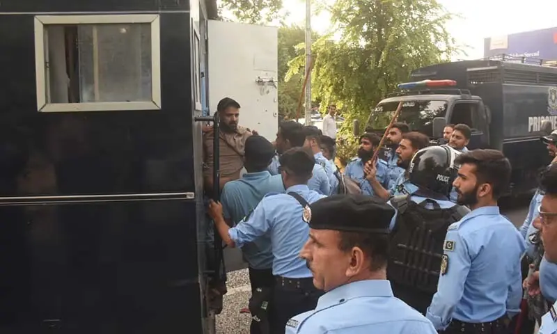 People are loaded into the back of a police van during a raid on the National Press Club in Islamabad on October 2. — Dawn