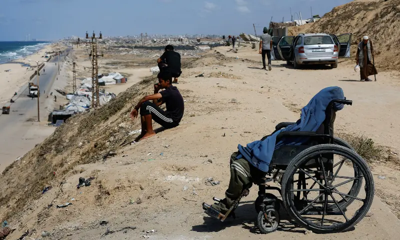 A displaced Palestinian man, who fled Gaza City due to an Israeli military operation, sits in a wheelchair, as he rests on the roadside, in the central Gaza Strip on October 5, 2025. — Reuters/Mahmoud Issa