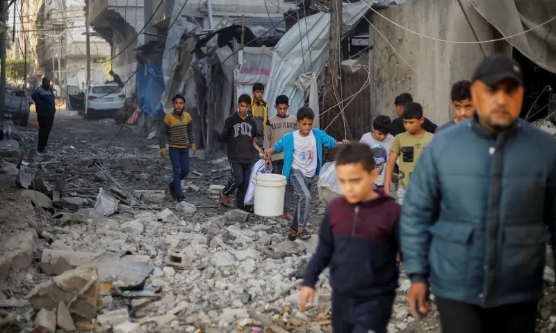 Palestinian children carry items as they walk at the site of Israeli strikes, amid the conflict between Israel and Hamas, in Khan Younis in the southern Gaza Strip, on December 6, 2023. — Reuters