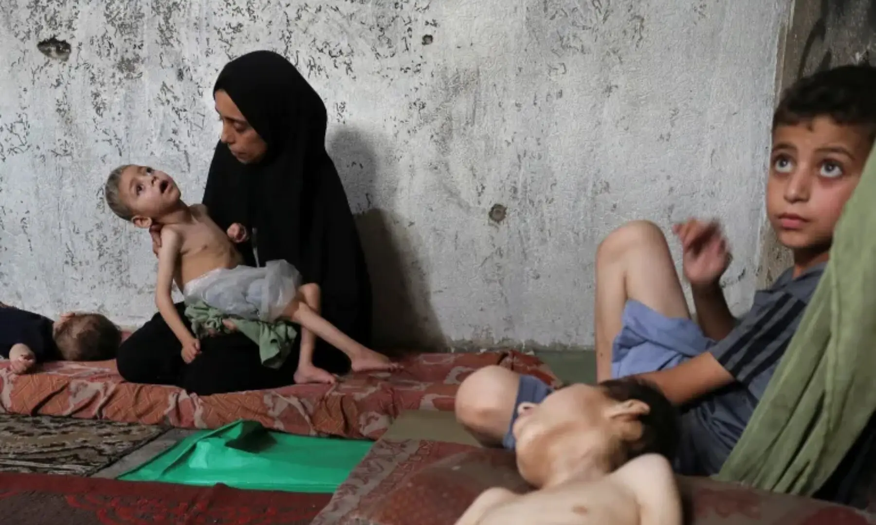   Displaced Palestinian mother Samah Matar holds her malnourished son, Ameer, who suffers from cerebral palsy, as her other son Youssef, also malnourished and suffering from cerebral palsy, lies on a mattress at a school in Gaza City. — Reuters  