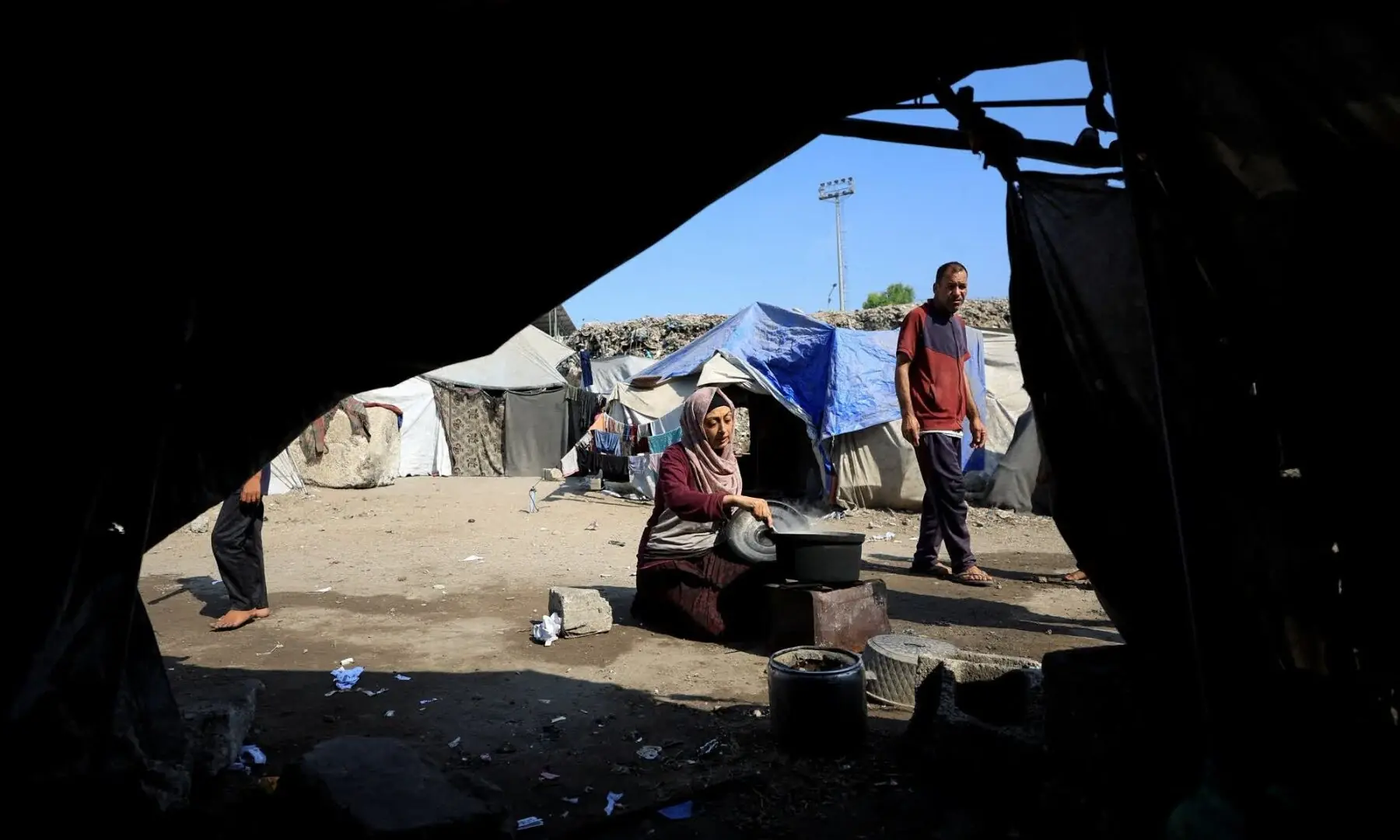   A displaced Palestinian woman cooks amid ongoing food shortages in Gaza on July 28. — Reuters  