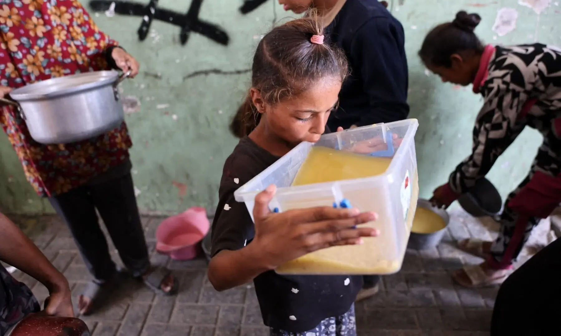   A displaced Palestinian girl takes a sip of lentil soup that she received at a food distribution point in Gaza City on July 25. — AFP  