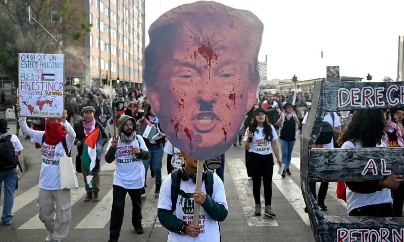 A demonstrator holds a sign depicting US President Donald Trump during a march in Bogota, Colombia, Oct 7. &mdash; AFP