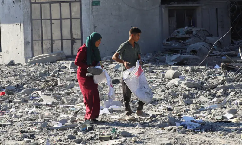 Palestinians walk as they inspect through a damaged neighbourhood in the aftermath of an Israeli operation, after Israel&rsquo;s government ratified a ceasefire with Hamas, in Gaza City, on October 10, 2025. &mdash; Reuters