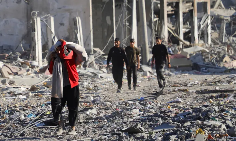 A Palestinian carrying belongings walks through a damaged neighbourhood in the aftermath of an Israeli operation, after Israel&rsquo;s government ratified a ceasefire with Hamas, in Gaza City, on October 10, 2025. &mdash; Reuters