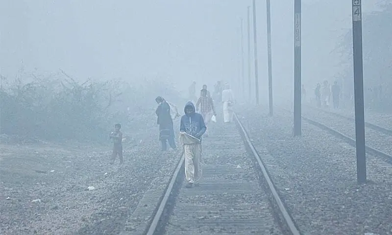 In this file photo, people cross the railway track in the Walton area of Lahore during foggy weather. &mdash; Online/File