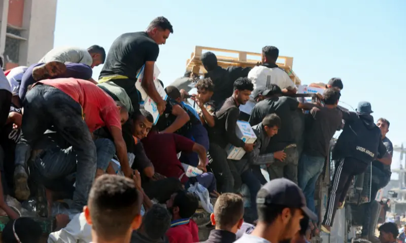 Palestinians collect aid supplies from a truck that entered Gaza, amid a ceasefire between Israel and Hamas, in Khan Younis, in the southern Gaza Strip, on October 12, 2025. &mdash; Reuters