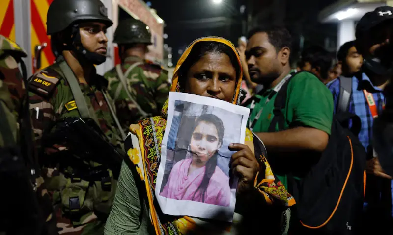 A relative mourns while holding a picture of a missing girl following a fire that broke out at a garment factory and a chemical warehouse in Dhaka, Bangladesh, on October 14. — Reuters