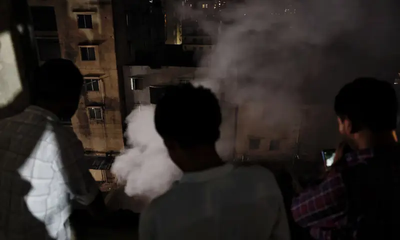 Onlookers watch fire from a multi-storey building that broke out at a garment factory and a chemical warehouse in Dhaka, Bangladesh, on October 14. — Reuters