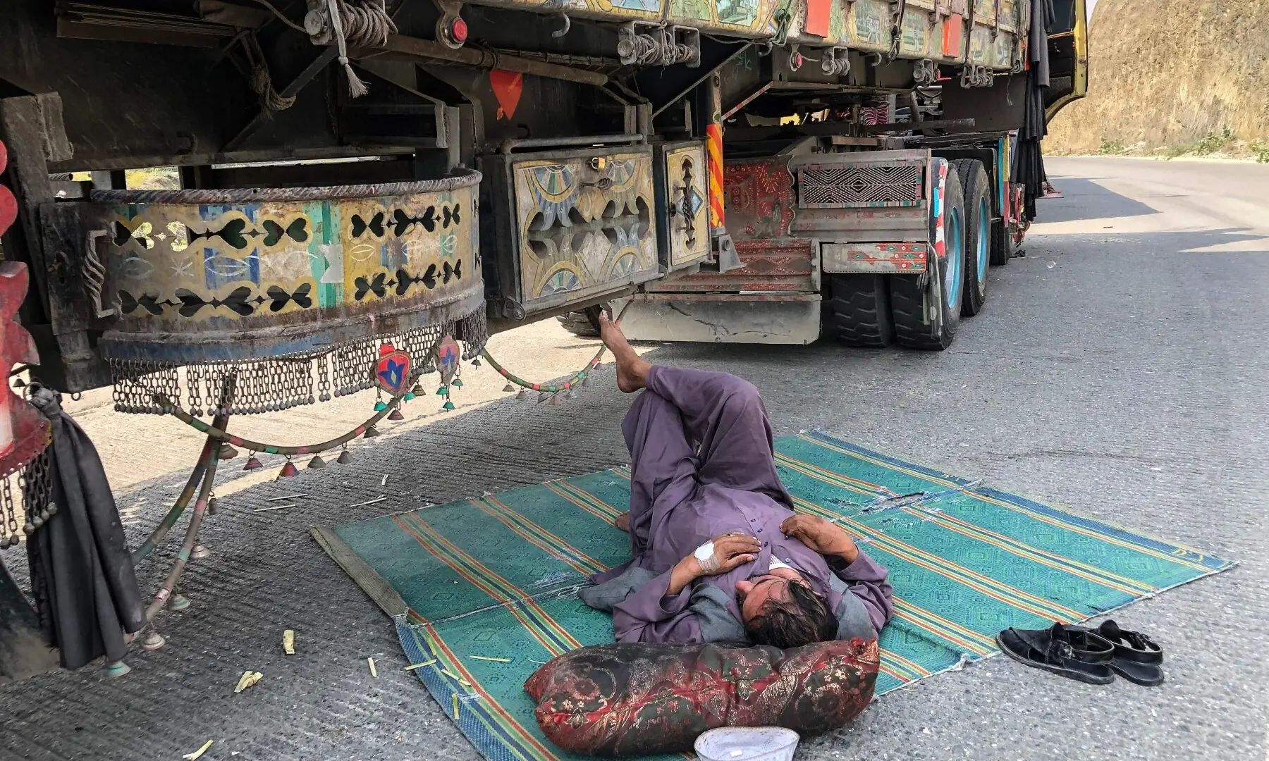  A truck driver rests beside his stalled vehicle along a road near the closed Pakistan-Afghanistan border town of Torkham, Pakistan, October 19. &mdash; AFP 