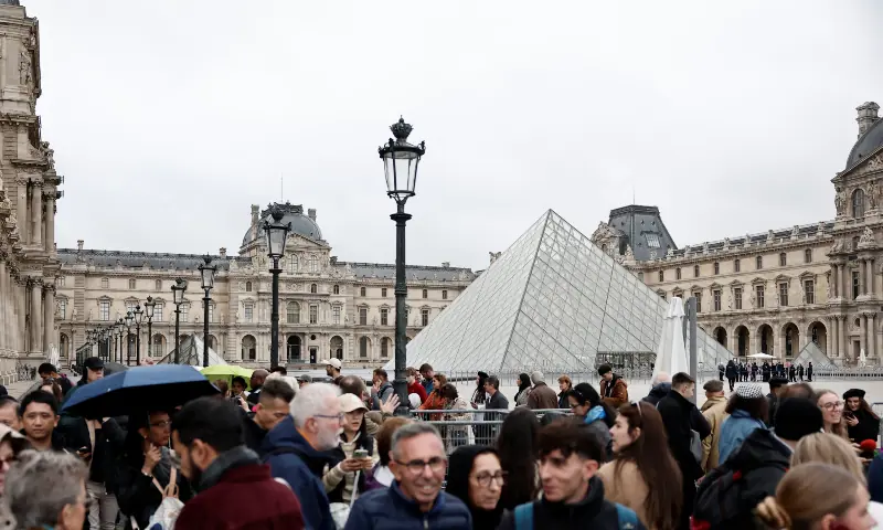 Visitors stand near the glass Pyramid of the Louvre Museum as the museum remains closed the day after a spectacular jewel heist by thieves who broke into the landmark by using a crane and smashing an upstairs window, stealing priceless jewelry from an area that houses the French crown jewels before escaping on motorbikes, in Paris, France on Oct 20, 2025. &mdash; Reuters