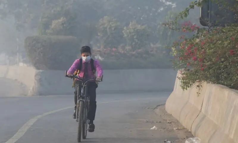 A student rides a bicycle to school amid dense smog in Lahore, November 24, 2021. &mdash; Reuters/File