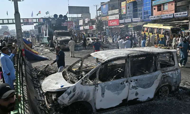 Locals walk past the remains of charred vehicles following violent clashes between police personnel and anti-Israel protesters from the Tehreek-e-Labbaik Pakistan (TLP) party in Muridke on October 13, 2025. &mdash; AFP