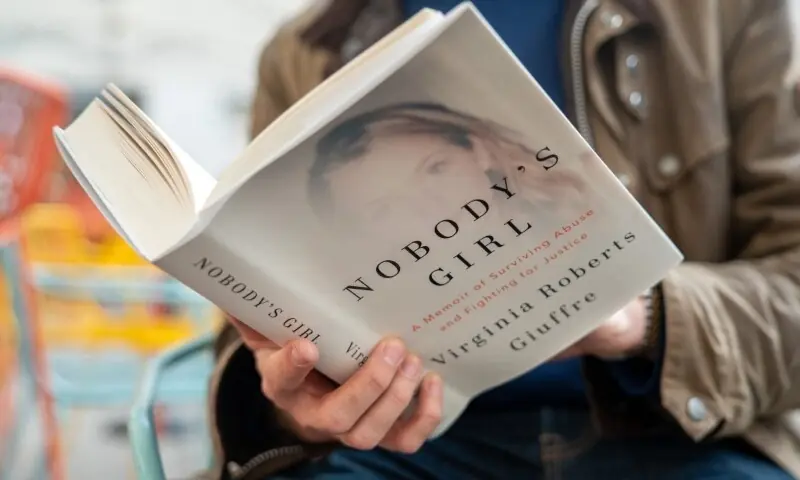 A person poses for a photo with a copy of the book &ldquo;Nobody&rsquo;s Girl - A Memoir of Surviving Abuse and Fighting for Justice&rdquo; by Virginia Roberts Giuffre, in central London on October 21. &mdash;AFP