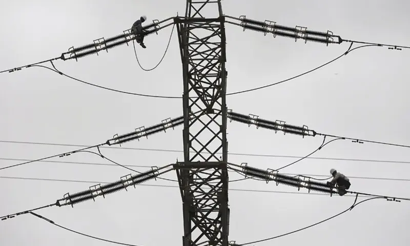 Technicians fix cables on a power transmission tower in this file photo. — Reuters Technicians fix cables on a power transmission tower in this file photo. — Reuters