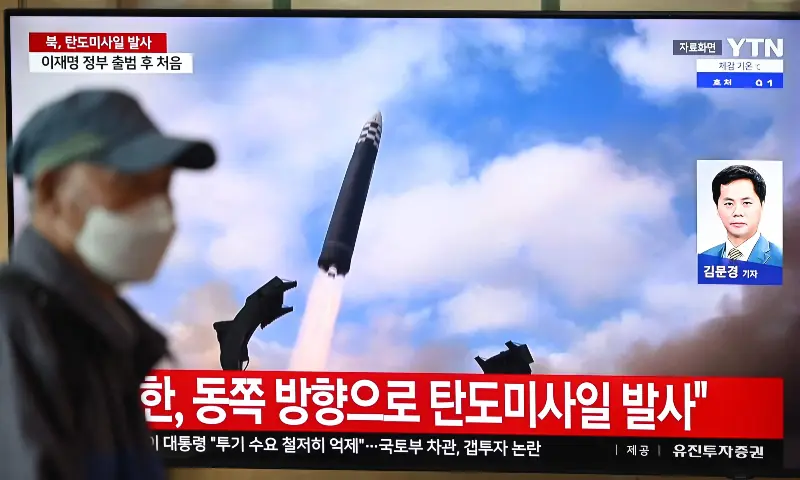 A man walks past a television screen showing a news broadcast with file footage of a North Korean missile test, at a train station in Seoul on October 22, 2025. &mdash; AFP