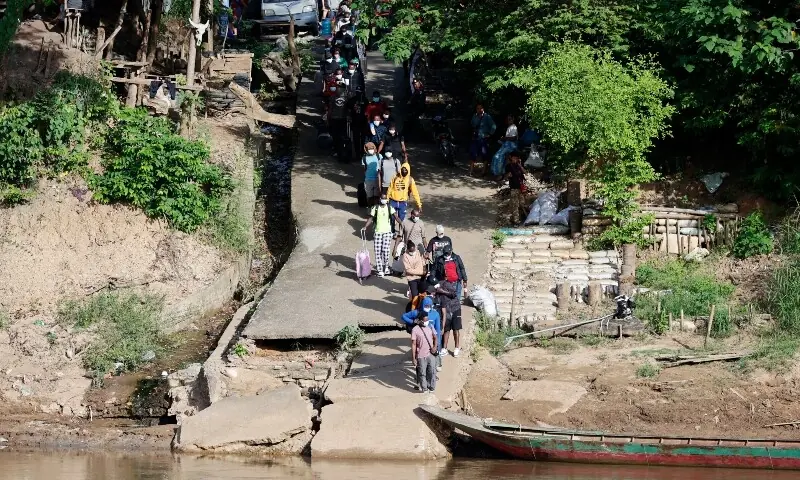 People from various countries, who were working in the KK Park compound in Myanmar, wait to board a boat with their belongings to cross over from Myanmar to Thailand via the Moei river, as seen from Mae Sot District, Tak Province area on October 24. &mdash;AFP