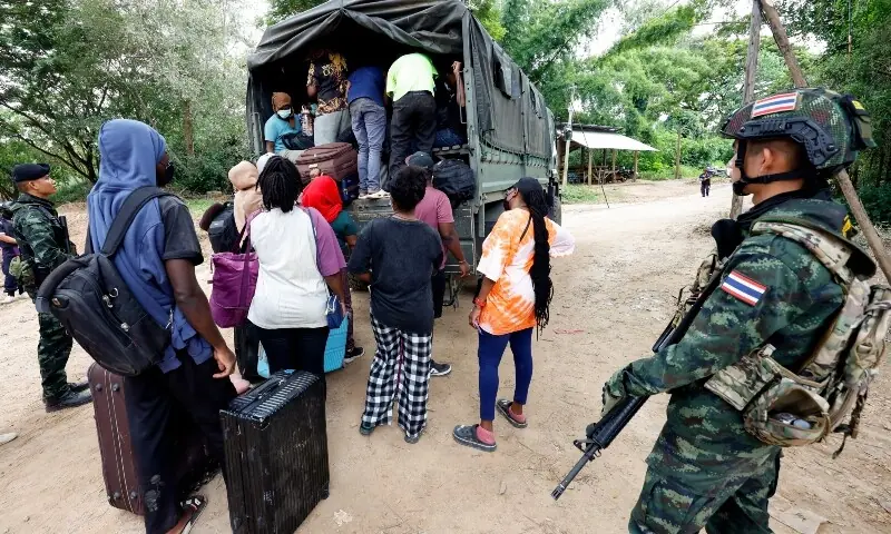 People from various countries, who were working in the KK Park compound in Myanmar and crossed to Thailand via the Moei river, board a vehicle as Thai soldiers keep watch in Mae Sot District, Tak Province area on October 24. &mdash; AFP