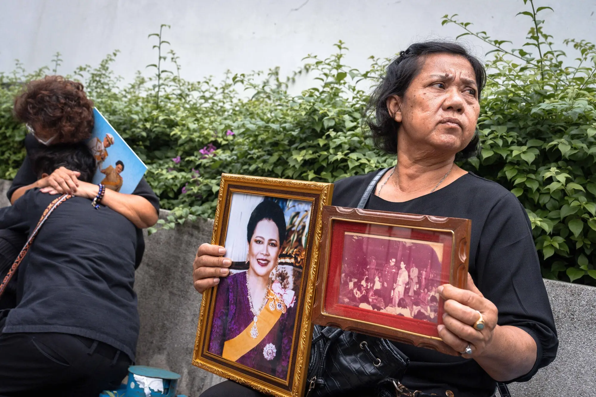     Shop owner Tanyaporn Arammetha (right) holds portraits of former Thai queen Sirikit in front of Chulalongkorn hospital in Bangkok on October 25. — AFP 