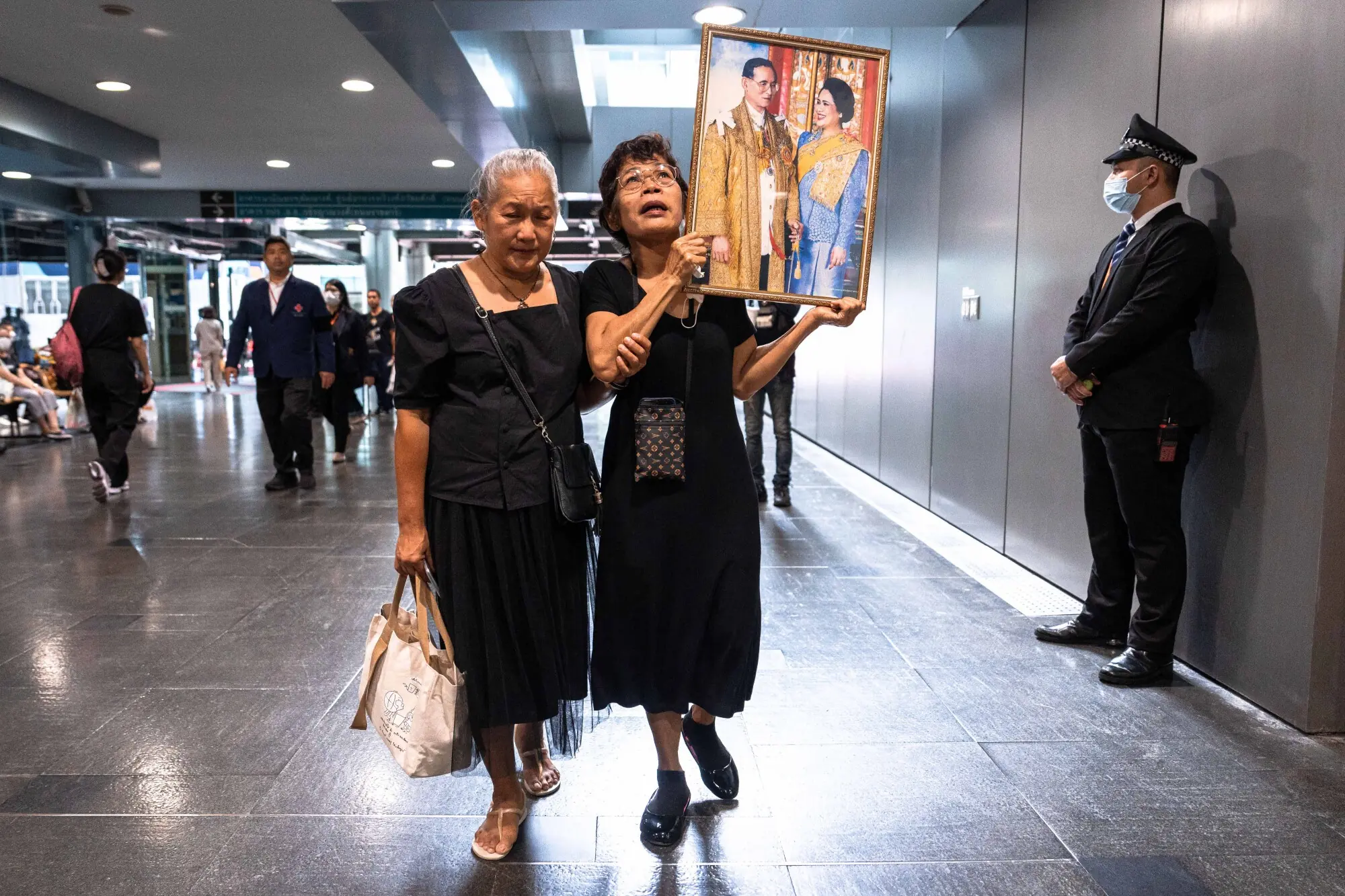     Thai mourners hold a portrait of former Thai Queen Sirikit with the late Thai King Bhumibol Adulyadej as they walk through Bangkok's Chulalongkorn Hospital on October 25. — AFP 